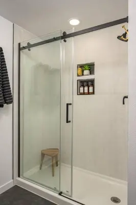 a glass shower with a stool in a bathroom at The Wild Rose Gatehouse in Arvada