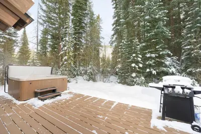 a snow covered deck with a grill and snow covered trees at Trailside Mountain Retreat with Private Hot Tub in Winter Park