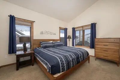 a bedroom with a bed and a dresser and windows at Hot Tub Mountain Views Steps to Trails in Winter Park