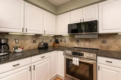a kitchen with white cabinets and a stove top oven at Luxe Home Minutes To Skiing Hot Tub in Winter Park