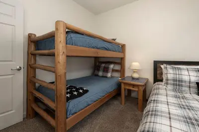 a bedroom with a bunk bed with a blue bedspread at Luxe Home Minutes To Skiing Hot Tub in Winter Park