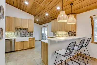 a kitchen with wooden cabinets and bar stools at Mountain Mansion with Hot Tub and Sauna in Morrison