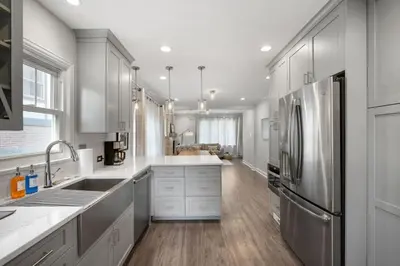 a kitchen with white cabinets and a stainless steel refrigerator at DU Cherry Creek Bungalow Sleeps 4 in Denver