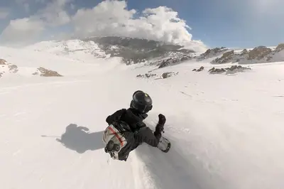 a man riding a snowboard down a snow covered slope at Winter Park Chalet I Mtn Biking I Summer festivals in Winter Park