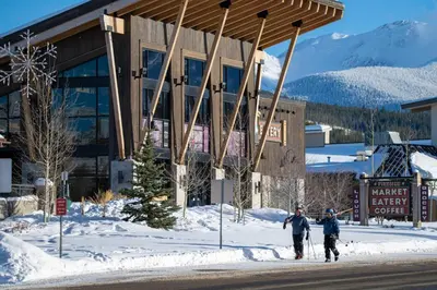 three people walking in the snow in front of a building at Winter Park Chalet I Mtn Biking I Summer festivals in Winter Park