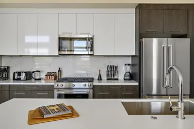 a kitchen with white cabinets and stainless steel appliances at 2880 Modern Lifestyle Loft at Espadin in Denver