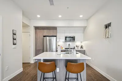 a kitchen with a white counter top and two stools at 2880 Sophistication Simplified at Espadin in Denver