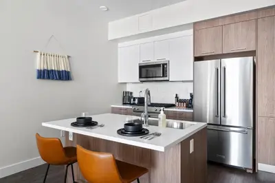 a kitchen with a stainless steel refrigerator and orange chairs at 2880 Sky-High LoHi Oasis at Espadin in Denver