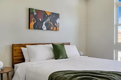 a bedroom with a bed with white sheets and green pillows at 2880 Canvas & Comfort at Espadin in Denver