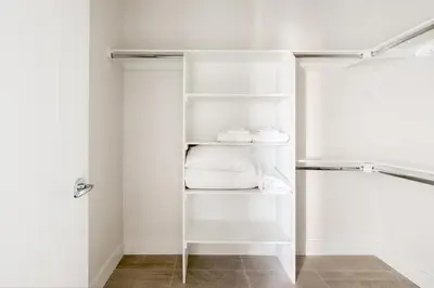 a white closet with white towels and shoes on shelves at 2880 Serenity in Style in Denver