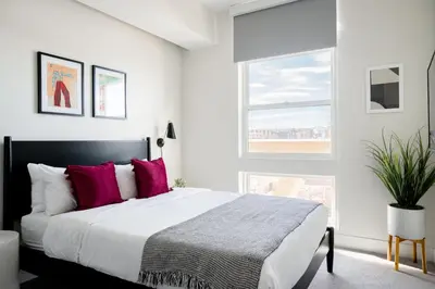 a white bedroom with a large bed with pink pillows at 2880 Serenity in Style in Denver