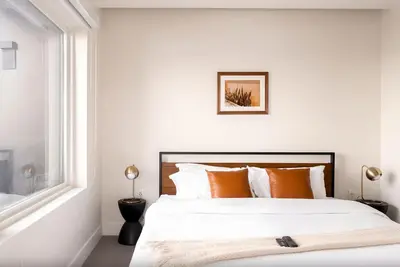 a white bedroom with a large bed with orange pillows at 2880 Denver Skyline Escape at Espadin in Denver