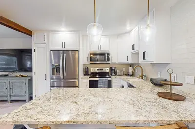 a kitchen with white cabinets and a marble counter top at SunSong Escape in Fraser