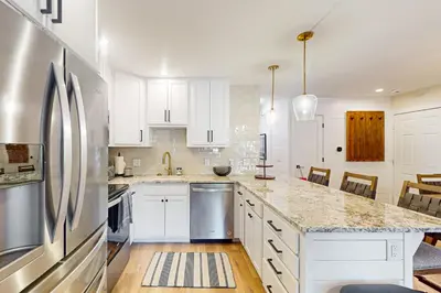 a kitchen with white cabinets and a stainless steel refrigerator at SunSong Escape in Fraser