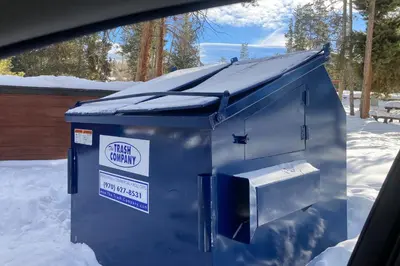 a blue dumpster with a sign on it in the snow at SunSong Escape in Fraser