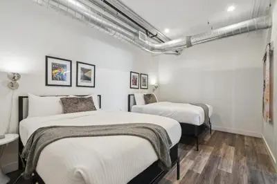 two beds in a room with white walls and wooden floors at RiNo Art Lofts in Denver