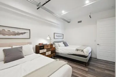 two beds in a room with white walls and wood floors at RiNo Art Lofts in Denver