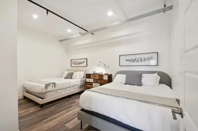 two beds in a bedroom with white walls and wood floors at 3198 Industrial Chic at RiNo Art Lofts in Denver
