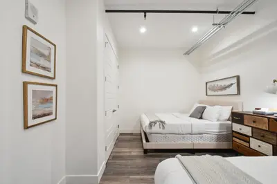 a white bedroom with two beds and a dresser at 3198 Industrial Chic at RiNo Art Lofts in Denver