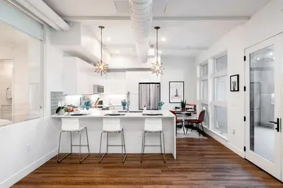 a kitchen with a white counter and stools at 3198 Bohemian Hideaway at RiNo Art Lofts in Denver