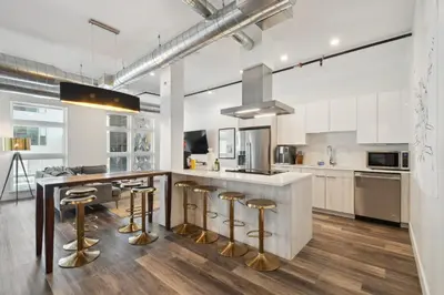 a kitchen with white cabinets and a counter with bar stools at 3198 Urban Cowboy Escape at RiNo Art Lofts in Denver