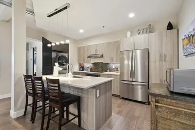 a kitchen with a island with chairs and a refrigerator at 3198 Graffiti & Skyline at RiNo Art Lofts in Denver