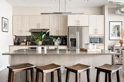 a kitchen with white cabinets and a counter with stools at 3198 Bright & Breezy at RiNo Art Lofts in Denver