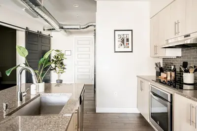 a kitchen with white cabinets and a sink at 3198 Bright & Breezy at RiNo Art Lofts in Denver