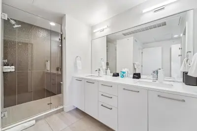 a white bathroom with a shower and two sinks at 2880 The Penthouse at Espadin in Denver