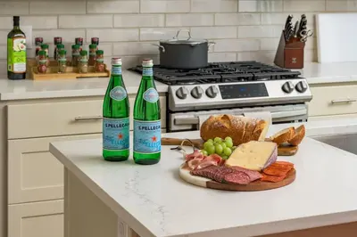 two bottles of wine and a plate of bread and grapes at Hot Tub with Rooftop a Game Room and 5 Bathrooms in Denver