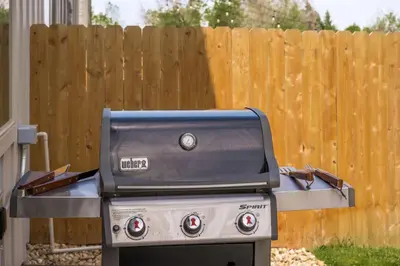 a grill sitting in front of a wooden fence at Hot Tub with Rooftop a Game Room and 5 Bathrooms in Denver