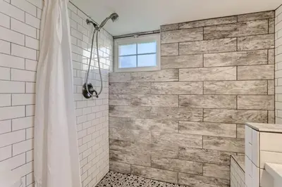 a bathroom with a shower with a stone wall at A Pet Friendly And Remodeled I Near RiNo Where Sleeps 7 in Denver