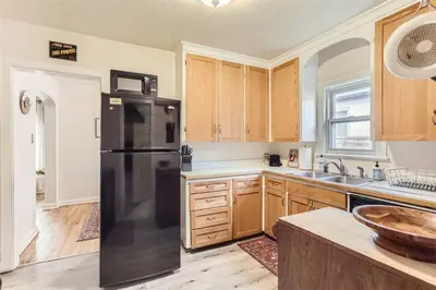 a kitchen with a black refrigerator and wooden cabinets at Cozy Duplex near Hospitals and Cherry Creek in Denver in Denver
