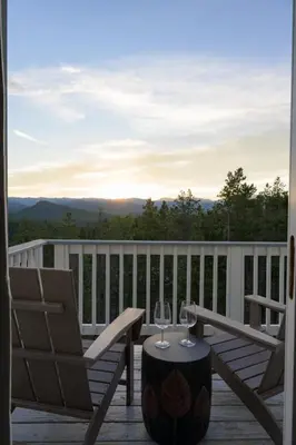 a patio with a chair and wine glasses on a deck at Luxe 4BR Mtn Retreat With Stunning Views Near Ski AndHikes in Nederland