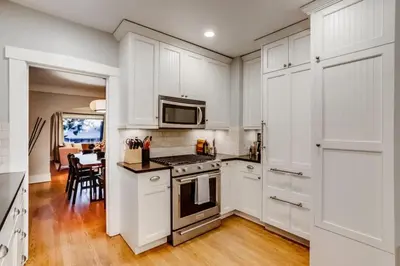 a kitchen with white cabinets and a stove top oven at The Bonsai Bungalow With A Hot Tub And A Game Room in Denver