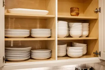a cabinet filled with white plates and bowls at The Bonsai Bungalow With A Hot Tub And A Game Room in Denver