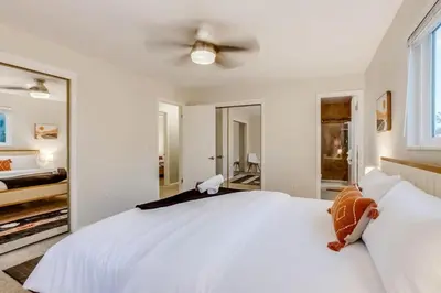a bedroom with a white bed with a ceiling fan at A Great Location Modern Home With A Hot Tub in Arvada