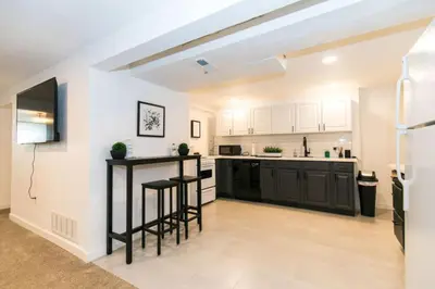 an open kitchen with black counter stools and white cabinets at Cozy With 2 Bath 10 min to Downtown Denver And Fast Wifi in Denver