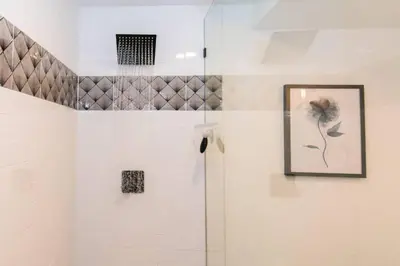 a bathroom with a shower with a picture on the wall at Cozy With 2 Bath 10 min to Downtown Denver And Fast Wifi in Denver