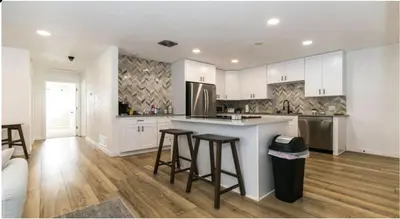 a kitchen with white cabinets and bar stools at Cozy With 2 Bath 10 min to Downtown Denver And Fast Wifi in Denver