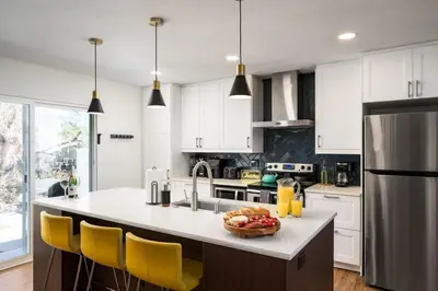 a kitchen with white cabinets and a kitchen island with yellow chairs at The MCM Movie Manor With A Big Backyard And A Movie Theater in Arvada