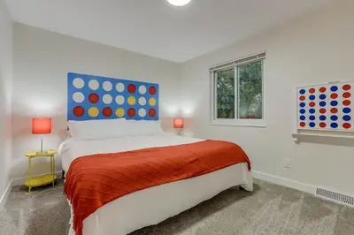a white bedroom with a large bed with a orange blanket at Games Gone Wild Between Red Rocks And Downtown Denver In Arvada in Arvada