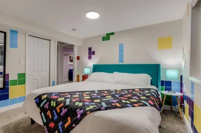 a bedroom with a bed with a colorful quilt on it at Games Gone Wild Between Red Rocks And Downtown Denver In Arvada in Arvada