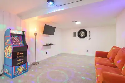 a room with a video game machine and a couch at Groovy Getaway With 4 KING Beds And A Hot Tub in Westminster