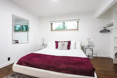 a white bedroom with a large bed with a red blanket at Groovy Getaway With 4 KING Beds And A Hot Tub in Westminster
