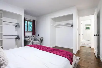 a white bedroom with a bed and a chair at Groovy Getaway With 4 KING Beds And A Hot Tub in Westminster