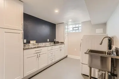 a kitchen with white cabinets and a black wall at Highlands Bungalow With A Back Yard And A Fire Pit in Denver