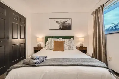 a bedroom with a bed with a cow picture on the wall at Modern Home In West Denver 15 Min Close To Downtown in Westminster