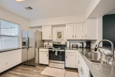 a kitchen with white cabinets and a stainless steel refrigerator at Modern Home In West Denver 15 Min Close To Downtown in Westminster