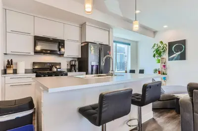 a kitchen with white cabinets and a bar with chairs at 3 Bedrooms 2 Bath Townhome In West Denver Near to Red Rocks And Foothills in Lakewood